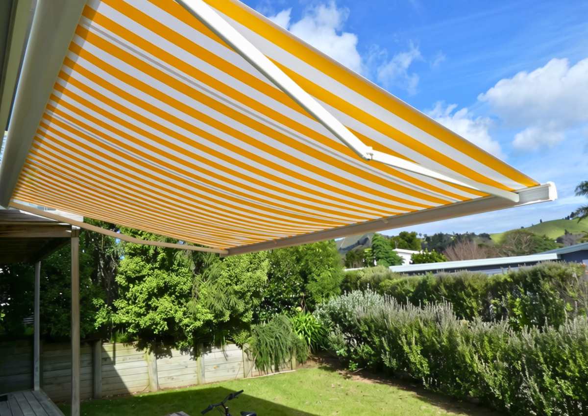 Yellow and white striped folding arm awning over a patio