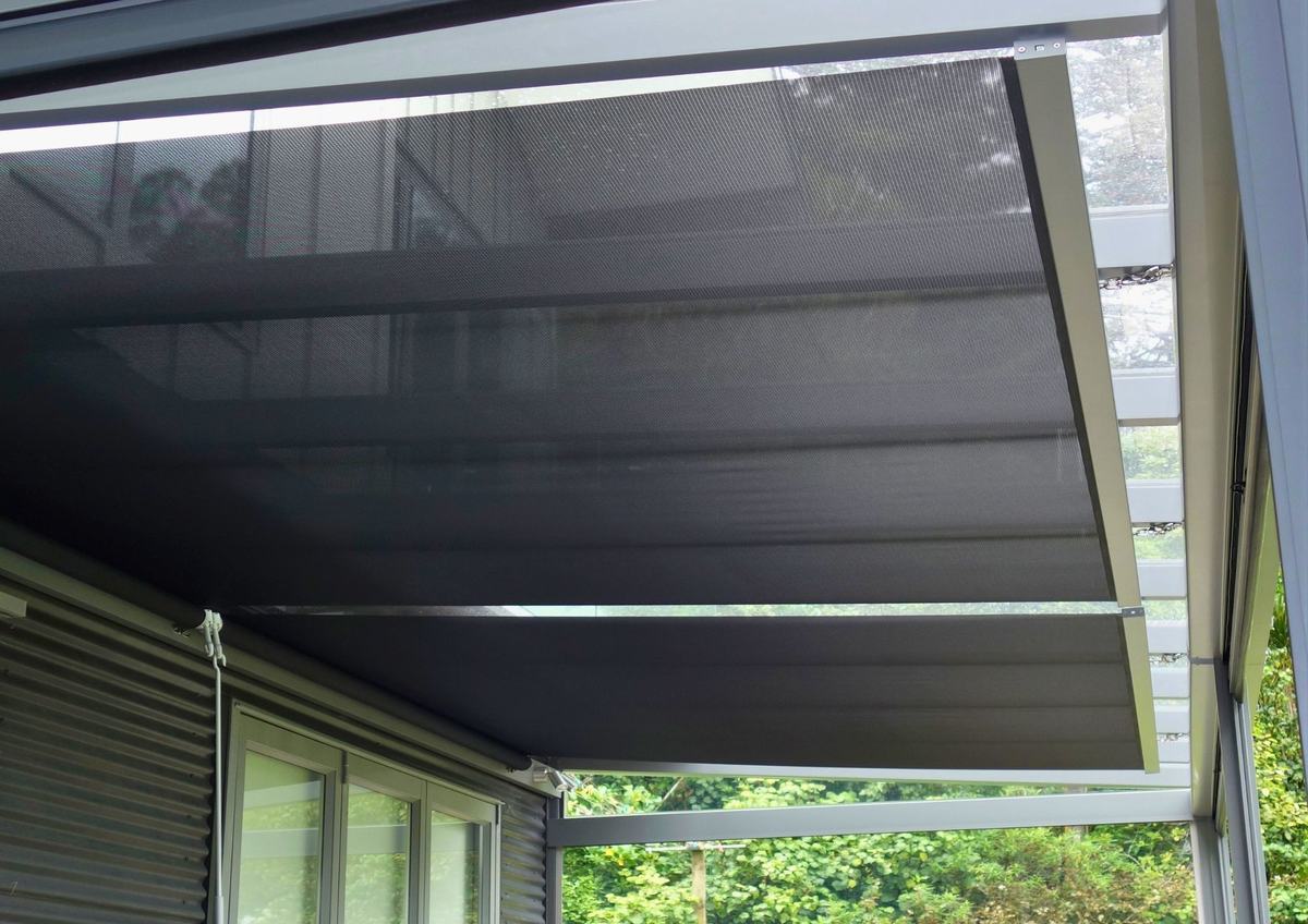 Outdoor mesh shade installed beneath a covered structure