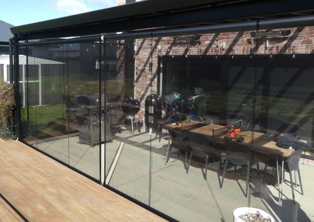 Dark mesh outdoor blinds enclosing a commercial patio